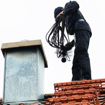 Chimney sweep standing on roof of home working